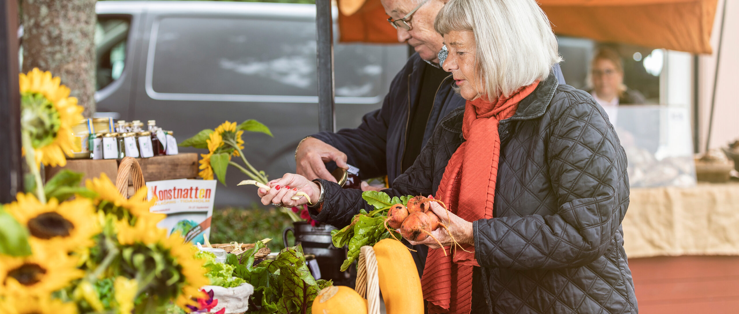 en man och en kvinna handlar grönsaker på torget